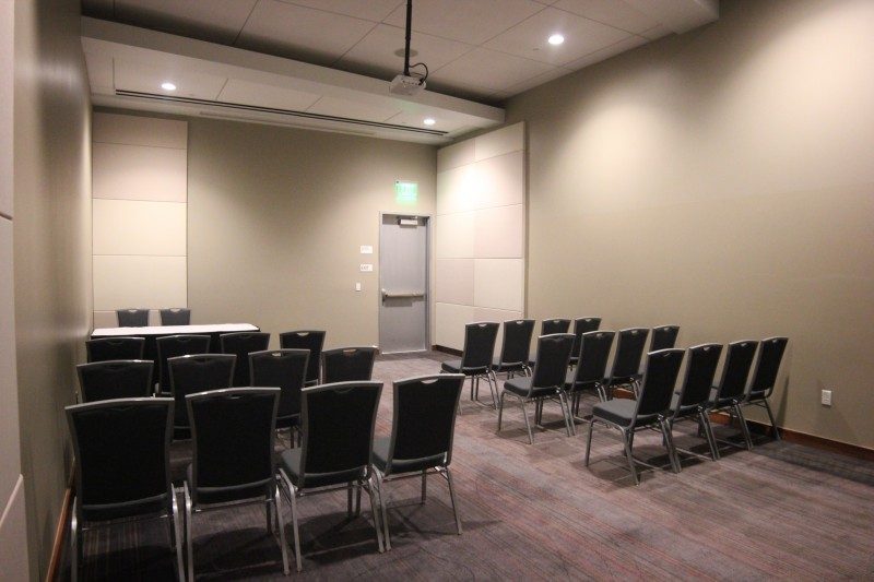 Modern meeting room with rows of chairs and beige walls.
