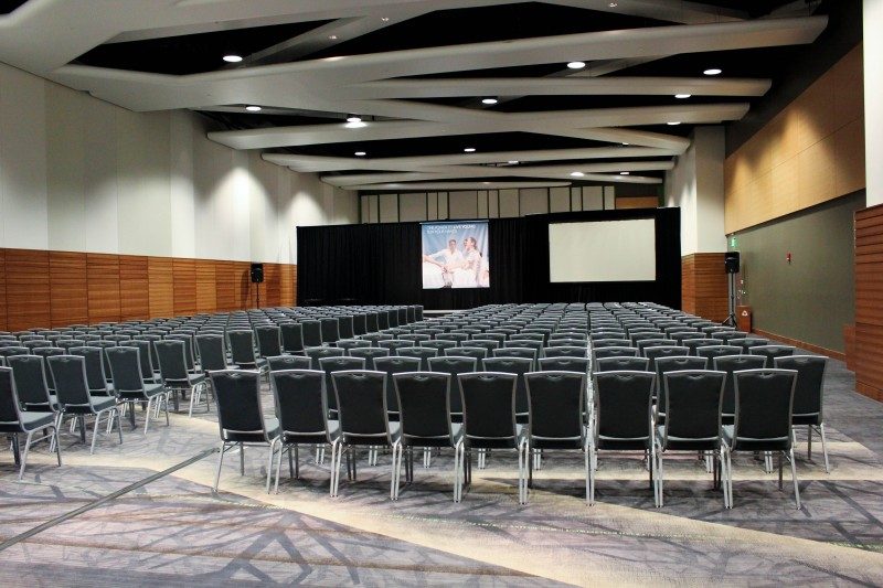 Empty conference room with rows of chairs facing a projection screen