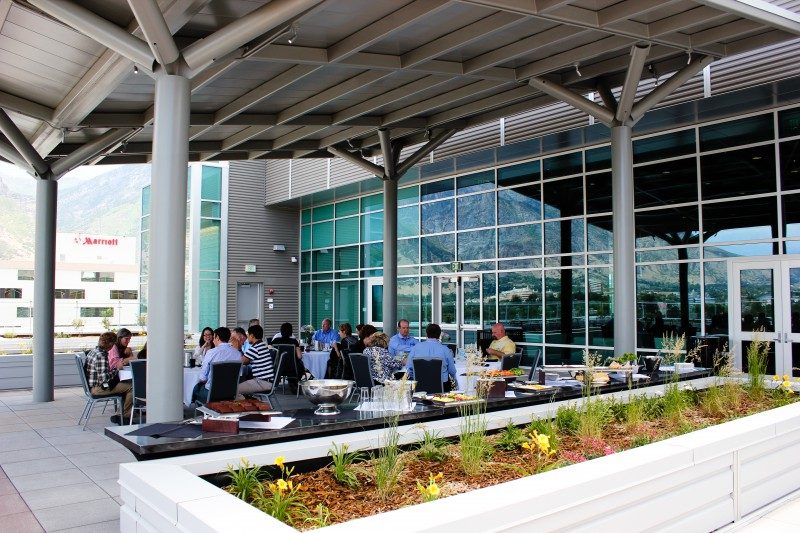 Outdoor dining area with people at tables near a modern building