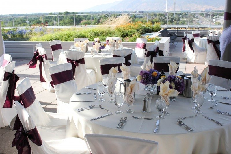 Outdoor event setup with tables, white linens, and purple accents