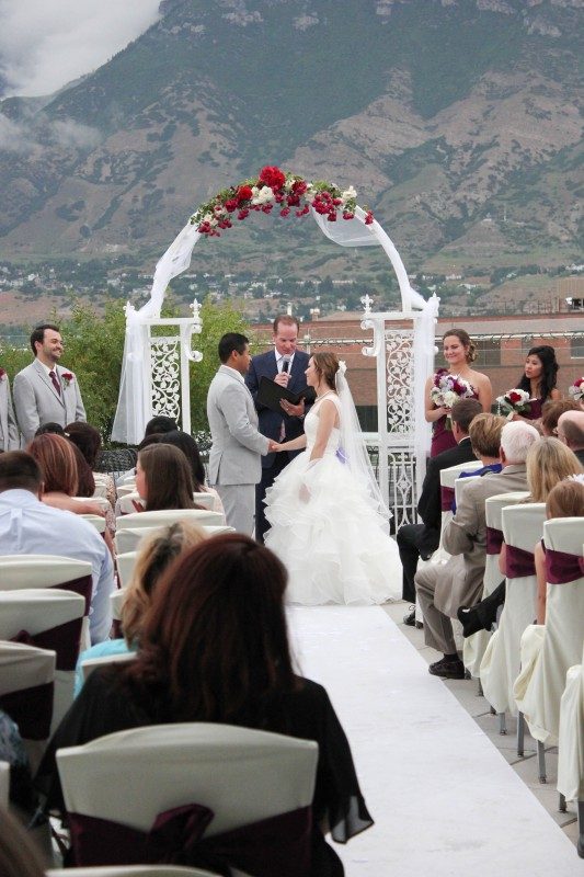 Bride and groom during wedding ceremony on a rooftop terrace . Tall mountains in the background.