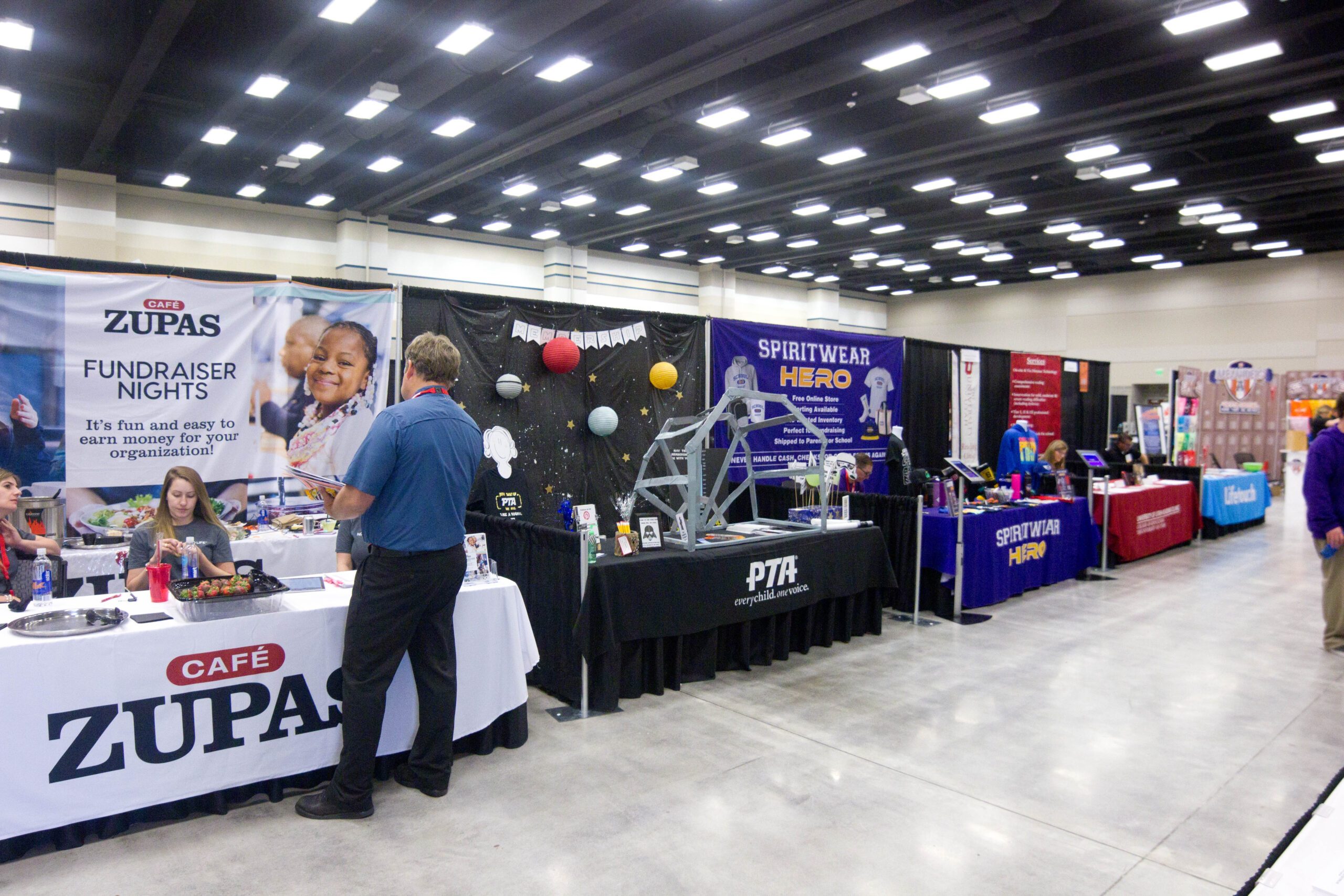 trade show booths with a man talking to a woman sitting at one of them.