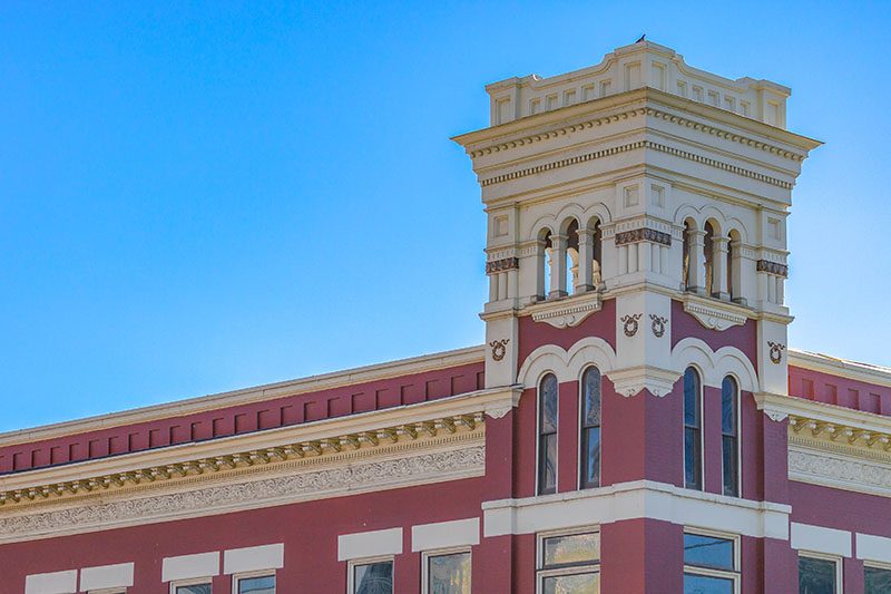 Building with corner tower in Provo against sky. View of a red and white building in Provo, Utah against clear blue sky. The beautiful building has a tower in the corner with arched windows.