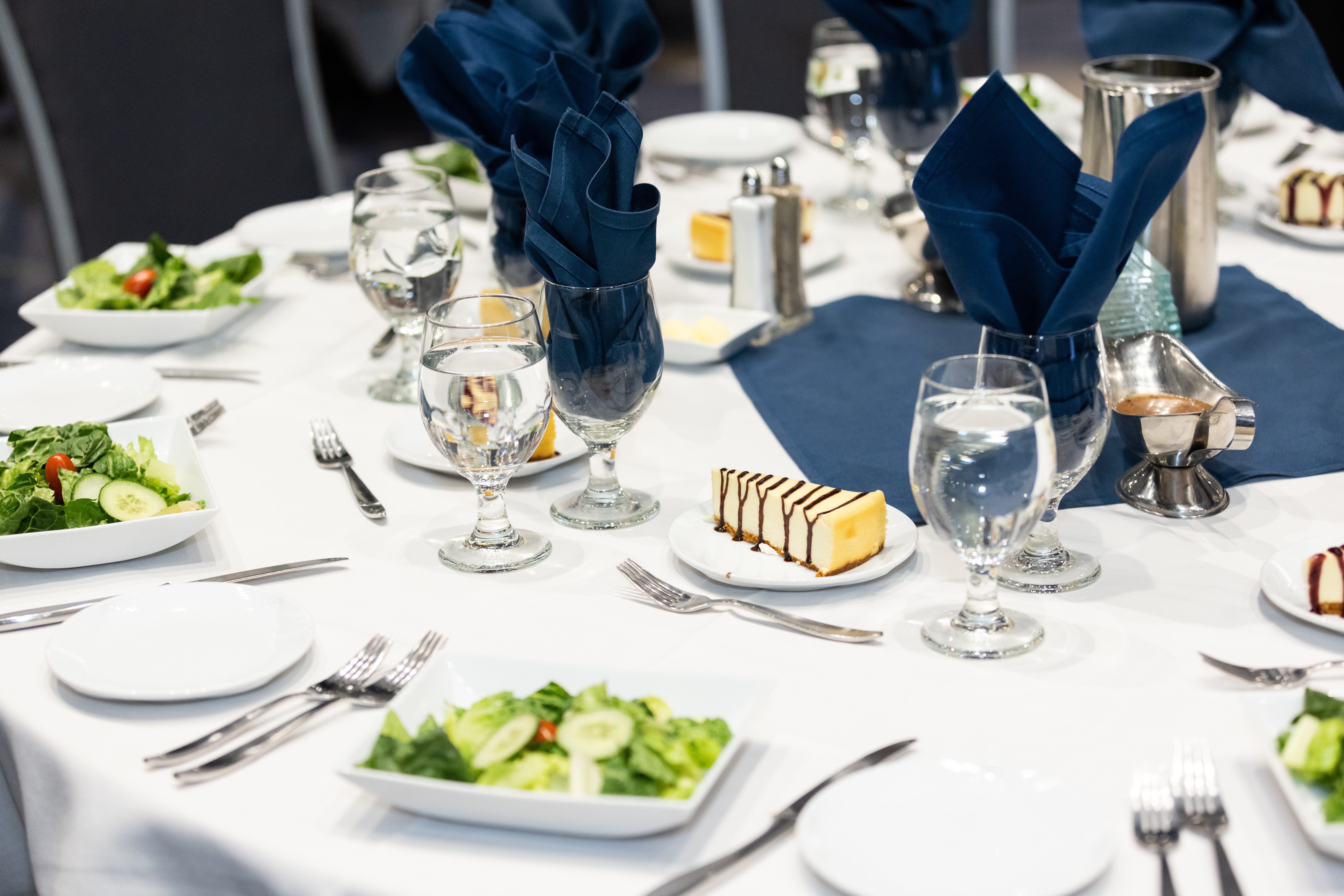 banquet set for fine dining with salads and desserts, goblets, plates.