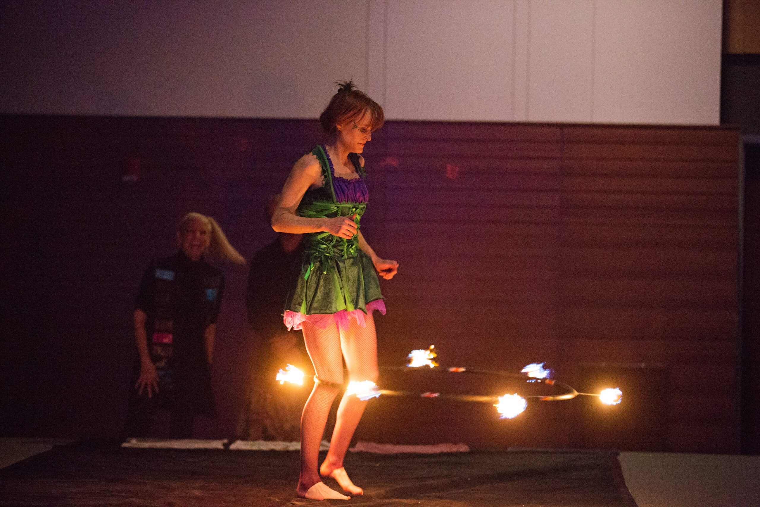 A woman spinning a flaming hula hoop onstage.