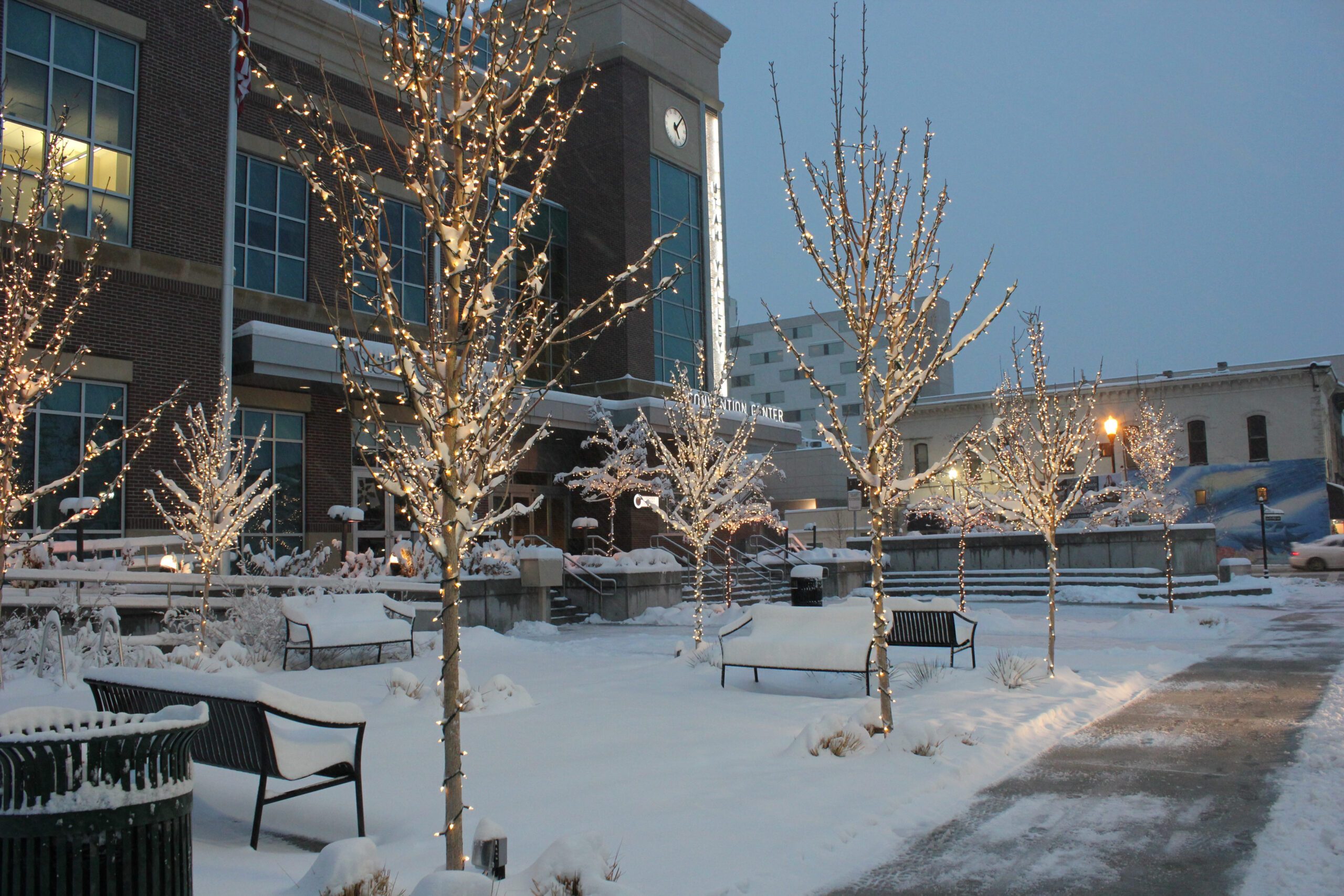 UVCC building covered with snow and illuminated trees at dusk