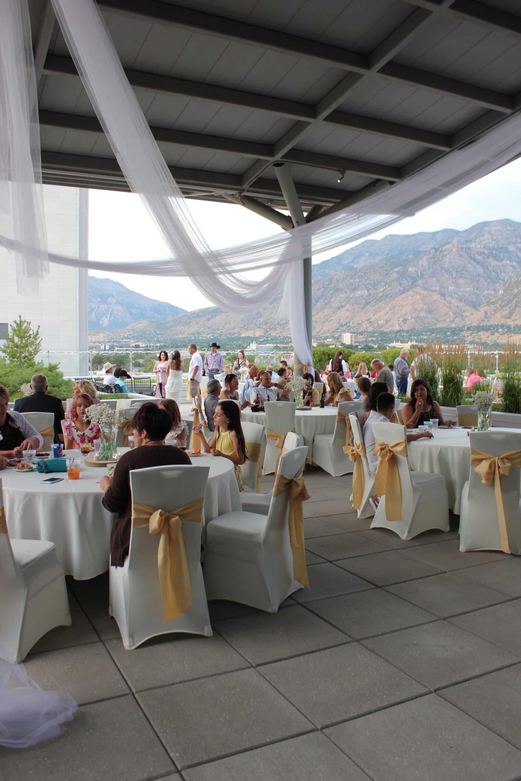 An outdoor event with guests at tables under a canopy